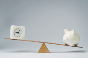 A visual metaphor of striking the Balance Between Immediate Results and Long-Term Success with a clock on the slightly higher left side of a seesaw with a piggy bank on the lower opposite end