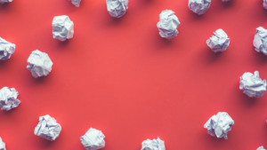 A photo of balled-up pieces of paper on a red background to represent why B2B martech investments fail