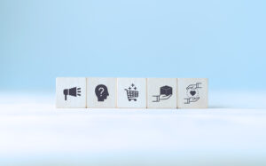 Customer Experience (CX) Vs. Demand Experience (DX) represented as a series of wooden blocks with various engagement channel icons on them
