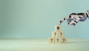 Strategic Approach to AI represented by building blocks with question marks and a robot hand touching the top of the block pyramid